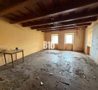 The interior of a family house with a wooden ceiling, an old table, and three windows.