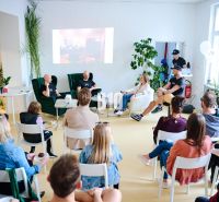 Discussion in the office with people sitting on chairs, with a projected image on the wall.