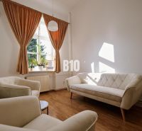 A bright office with comfortable cream sofas and a wooden decor floor.