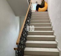 A person with a laptop is sitting on a yellow bean bag on the office stairs.
