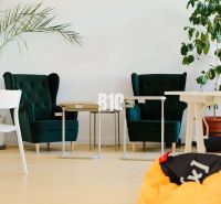 Offices with dark green chairs, white desks, and plants on a floor with wooden decor.