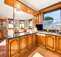 Traditional kitchen in a family house with wooden cabinets and a large window.