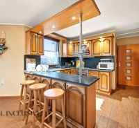 A kitchen in a family house with a bar counter and a wooden decor floor.