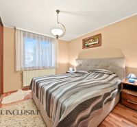 A bedroom in a family house with a wooden decor floor and a comfortable bed.