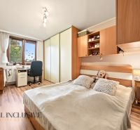 A bedroom in a family house with a bed, a desk, and a wooden decor floor.
