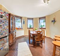A kitchen in a family house with a refrigerator, wooden furniture, and a floor with a wooden decor.