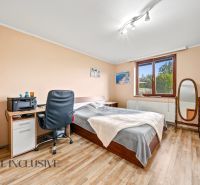 Bedroom in a family house with a bed, a desk, and a mirror, floor with wooden decor.