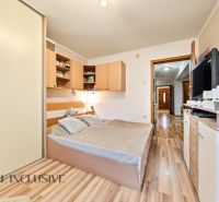 A bedroom in a family house with a wooden decor floor, a large bed, and a wardrobe.
