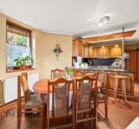 Dining area and kitchen in a family house with a wooden decor floor.