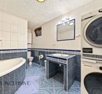 A bathroom with a shower, double sink, and washing machine in a family house.
