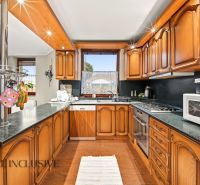 A kitchen with wooden cabinets and a wood-patterned floor in a family house.