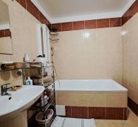 A bathroom with a bathtub and a sink in a 2-room apartment with tiled flooring.