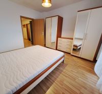 Bedroom in a two-room apartment with wood-patterned flooring and furniture.