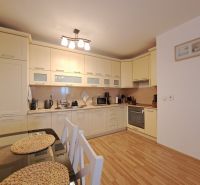 A kitchen in a 2-room apartment with a wooden decor floor and a dining table.