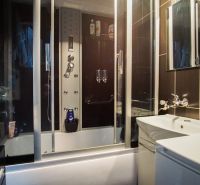 A bathroom in a 3-room apartment with dark tiles and a shower corner.