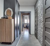 A hallway in a 3-room apartment with a wardrobe, a mirror, and stone cladding on the wall.