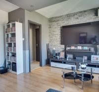 Living room in a 3-room apartment with a TV, brick cladding, and a wooden decor floor.
