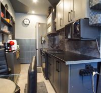 A stylish kitchen in a 3-room apartment with dark furniture and appliances.