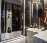 A bathroom in a 3-room apartment with a large shower and dark tiles.