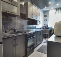 A kitchen in a 3-room apartment with gray cabinets and stainless steel appliances.