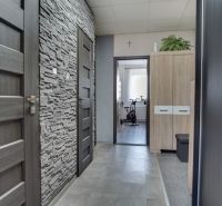 Entrance hall of a 3-room apartment with a stone wall imitation and gray doors.