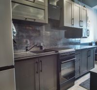 A kitchen in a 3-room apartment with gray cabinets and black appliances.