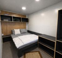 Bedroom in a holiday apartment with a bed and a shelving unit on the wall.