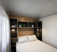 Bedroom in a holiday apartment with a bed, shelves, and details in wooden decor.
