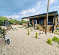 A recreational apartment in Sukošan with a terrace, gravel yard, and a swing bench.