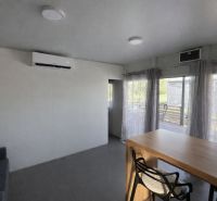 Interior of a holiday apartment with a sofa and wall-mounted air conditioning, light fixtures, and a table.
