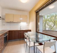 A kitchen in a 3-room apartment with a large window and a glass table.