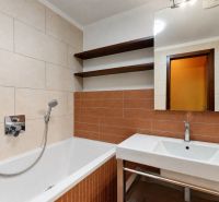 A bathroom with a bathtub, sink, and shelves in a 3-room apartment.