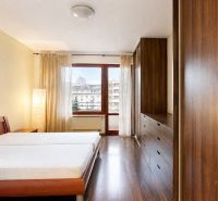 A bedroom in a three-room apartment with a wooden decor floor and a large window.