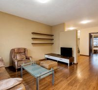 Living room in a three-room apartment with a leather sofa and a floor with a wooden decor.