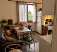 Interior of a 3-room apartment with a leather couch and a wood-patterned floor.