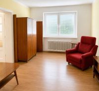 Living room in a family house with retro-style furniture and a wood-patterned floor.