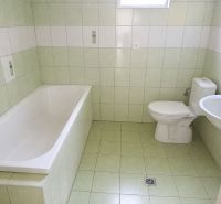 Bathroom in a family house with a bathtub and toilet, tiled with pastel tiles.