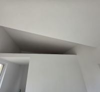 The interior of a cottage with a white ceiling and a view from the window.