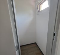 A small room in a cabin with a wooden decor floor and a narrow window.