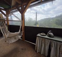 Hanging chair and table with kettles in a cottage with a view of the surroundings.
