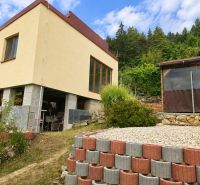A cottage on Tulská Street in Banská Bystrica surrounded by greenery and stones.