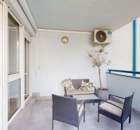 A balcony in a 3-room apartment with outdoor seating and a flower pot.