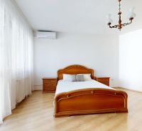 Bedroom with a wide window, bed, nightstands, and floor with wooden decor.