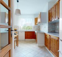 A kitchen with wooden cabinets and a tiled floor in a 3-room apartment.