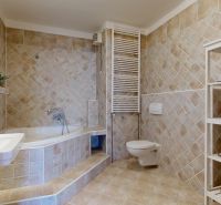 A bathroom with a bathtub, sink, toilet, and shelves in a 3-room apartment with ceramic tiles.