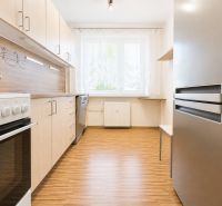 A kitchen in a 3-room apartment with a wooden decor, stove, and refrigerator.