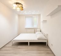 A bedroom with a white bed and a wooden decor floor in a 3-room apartment.