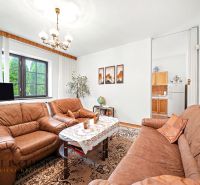 Living room in a family house with brown sofas and a floral patterned carpet.