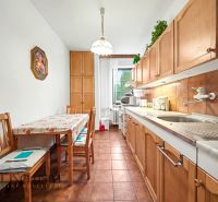 A kitchen in a family house with a long table, wooden chairs, and wooden cabinets.