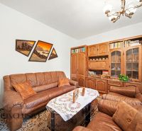 A living room in a family house with a brown sofa and wooden furniture.